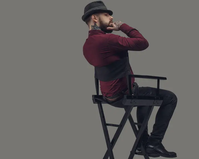 Man in hat sitting on film director's chair.