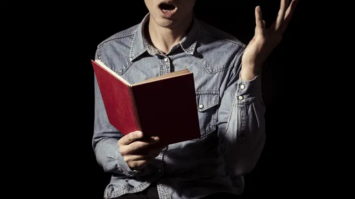 Close up of a man holding a book and reciting